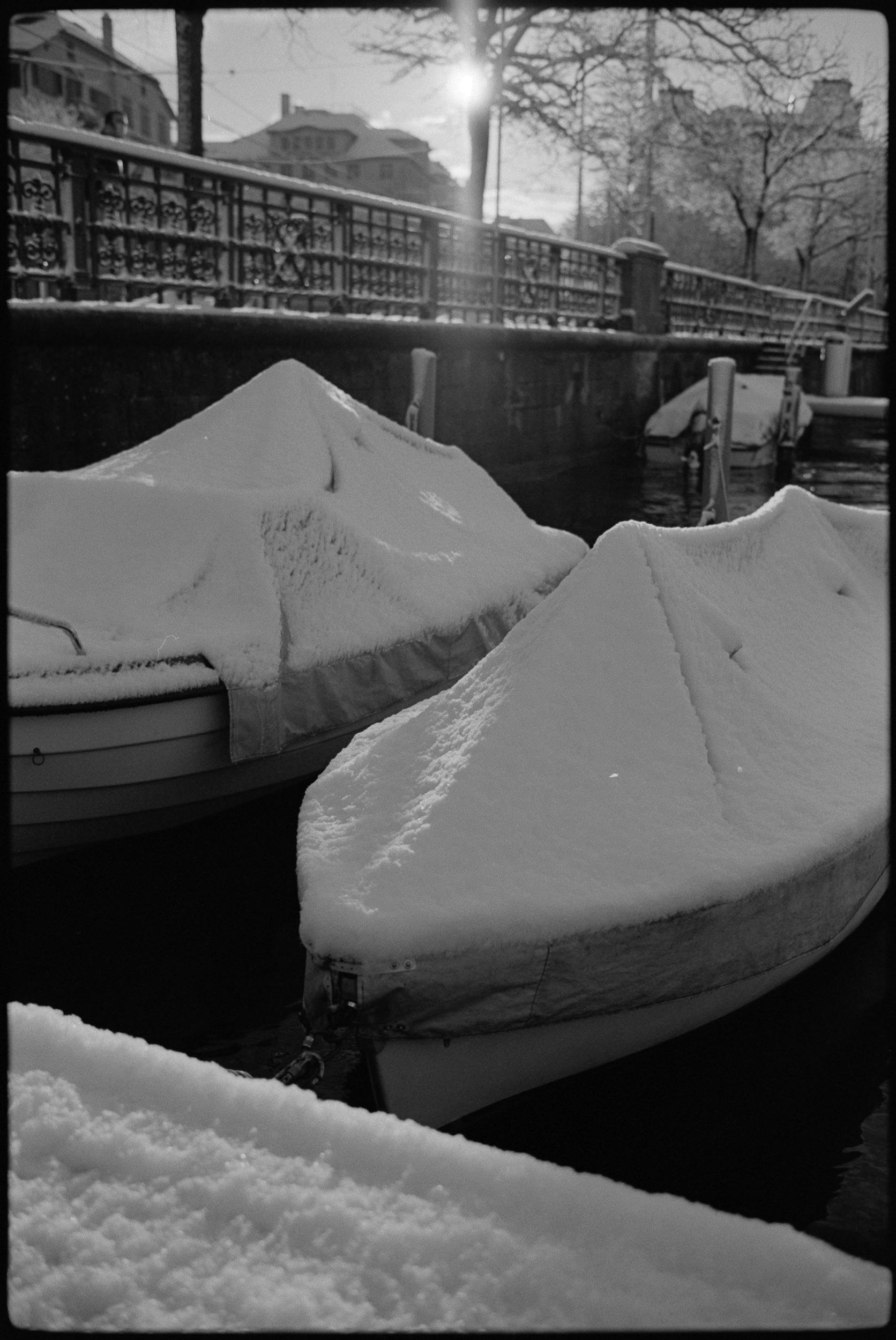 snow-covered boat with sun flare